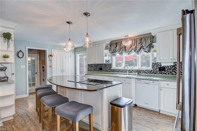 kitchen featuring a center island, stainless steel gas cooktop, white dishwasher, and white cabinets