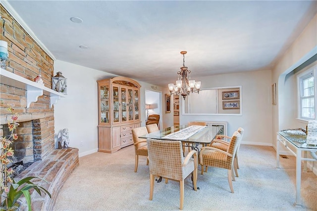 carpeted dining area with a brick fireplace and a chandelier