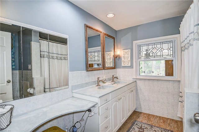 bathroom with walk in shower, wood-type flooring, vanity, and tile walls