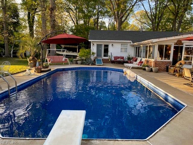 view of swimming pool with a diving board and a patio area