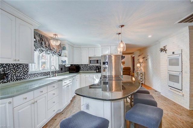 kitchen featuring stainless steel appliances, white cabinets, sink, a kitchen island, and light hardwood / wood-style flooring