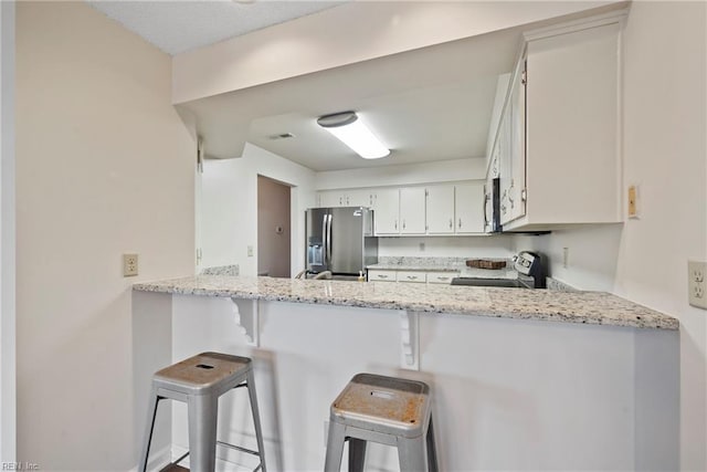157 Atlantic Ave Unit B2, Hampton, VA 23664 - kitchen featuring appliances with stainless steel finishes, a peninsula, light stone countertops, a breakfast bar area, and white cabinets