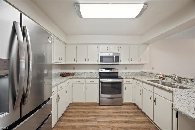 157 Atlantic Ave Unit B2, Hampton, VA 23664 - kitchen with stainless steel appliances, a sink, light wood-style floors, white cabinets, and light stone countertops