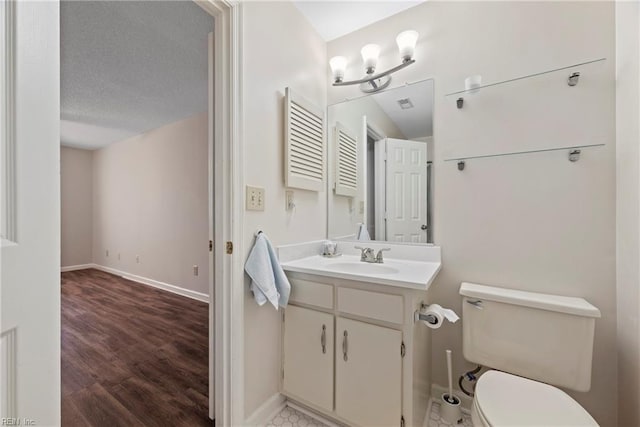 bathroom with toilet, vanity, hardwood / wood-style floors, and a textured ceiling