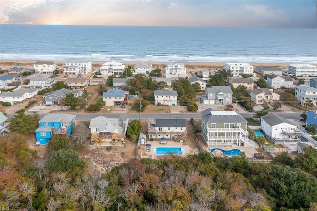 aerial view at dusk featuring a beach view and a water view