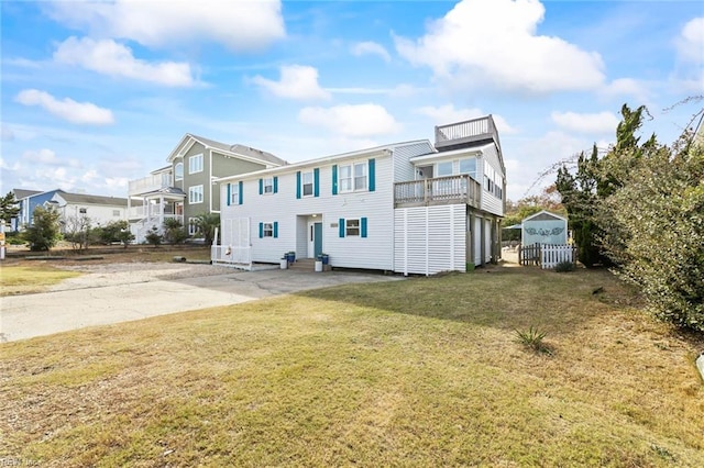 view of front of home with an outbuilding, a front lawn, and a balcony