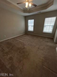 carpeted spare room featuring ceiling fan and a tray ceiling