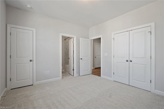 unfurnished bedroom featuring light carpet, a closet, and ensuite bath