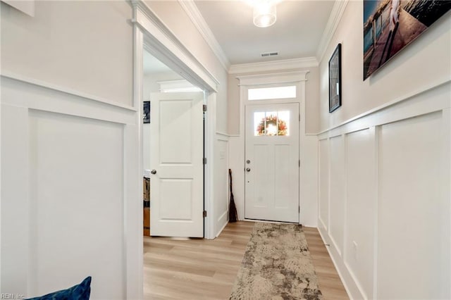 doorway to outside with light hardwood / wood-style floors and ornamental molding