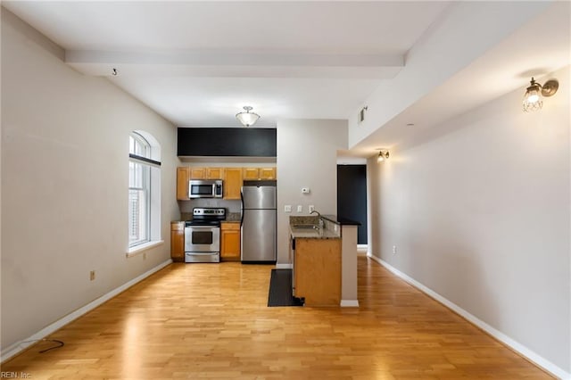 kitchen featuring beam ceiling, kitchen peninsula, sink, light hardwood / wood-style flooring, and stainless steel appliances