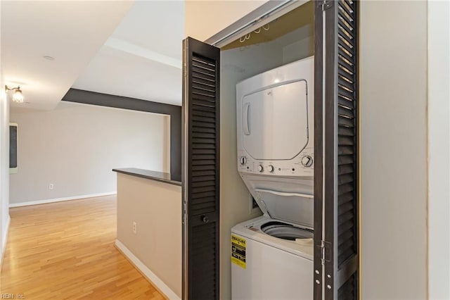 clothes washing area featuring stacked washer and dryer and wood-type flooring