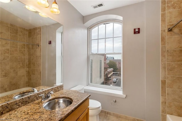 full bathroom with toilet, a healthy amount of sunlight, tile patterned flooring, and vanity