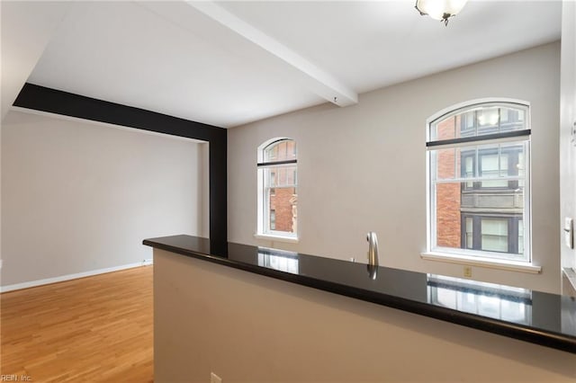 kitchen with a wealth of natural light, beam ceiling, and hardwood / wood-style floors