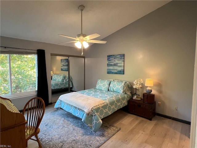 bedroom with a closet, light hardwood / wood-style floors, lofted ceiling, and ceiling fan