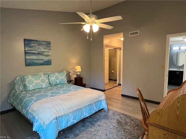 bedroom with ensuite bathroom, ceiling fan, light hardwood / wood-style flooring, a closet, and vaulted ceiling