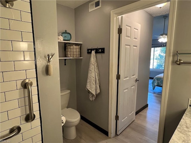 bathroom featuring toilet, a textured ceiling, hardwood / wood-style flooring, and ceiling fan