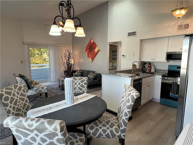 kitchen with white cabinets, decorative light fixtures, and stainless steel appliances