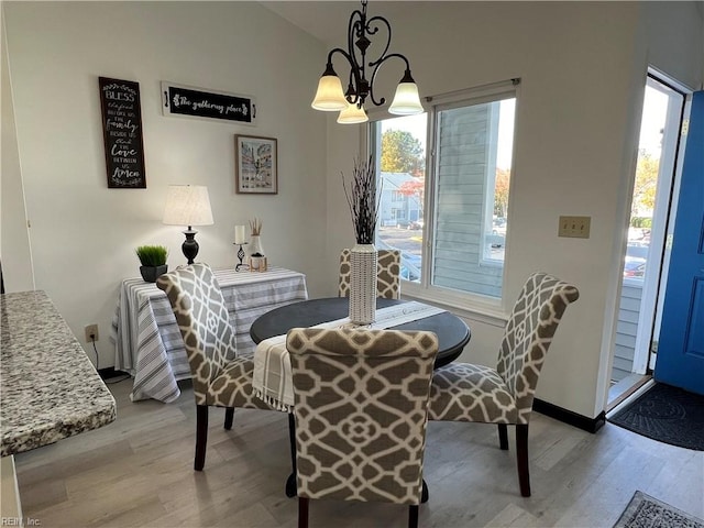 dining area with lofted ceiling, an inviting chandelier, light hardwood / wood-style floors, and plenty of natural light