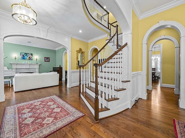 foyer with dark wood-type flooring, a chandelier, and crown molding