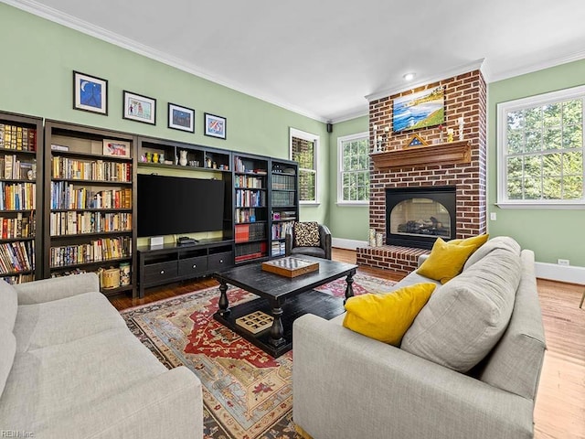 living room with a brick fireplace, hardwood / wood-style floors, crown molding, and plenty of natural light