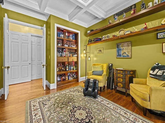 living area with wood-type flooring, coffered ceiling, ornamental molding, bar, and beam ceiling