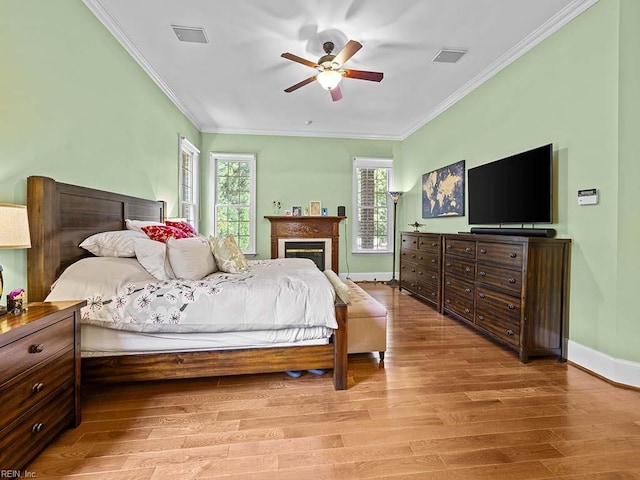 bedroom featuring light wood-type flooring, multiple windows, ceiling fan, and crown molding