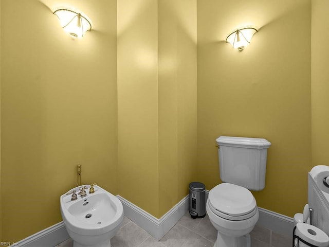 bathroom with toilet, a bidet, and tile patterned floors