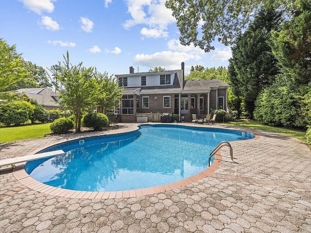 view of pool with a diving board and a patio