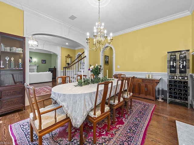 dining area with ornamental molding, dark wood-type flooring, and a notable chandelier