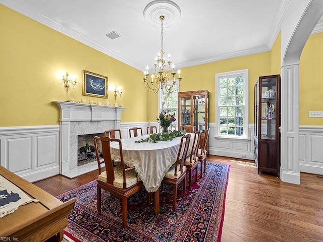 dining room with a chandelier, a high end fireplace, dark hardwood / wood-style floors, and crown molding