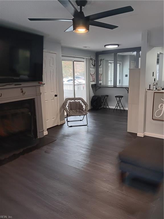 living room featuring dark wood-type flooring and ceiling fan