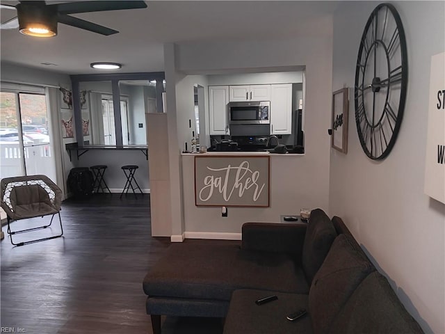 living room featuring ceiling fan and dark hardwood / wood-style flooring