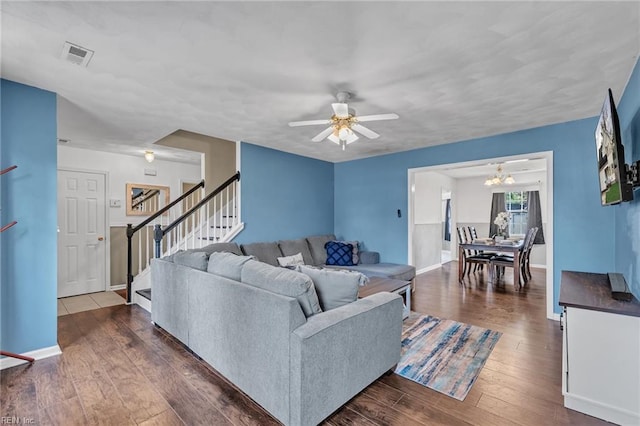 living room with ceiling fan with notable chandelier and dark hardwood / wood-style floors