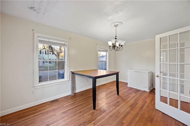 unfurnished dining area featuring a chandelier, a wealth of natural light, and hardwood / wood-style flooring