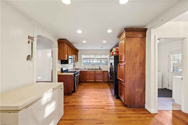 kitchen with stainless steel appliances, sink, and light hardwood / wood-style flooring