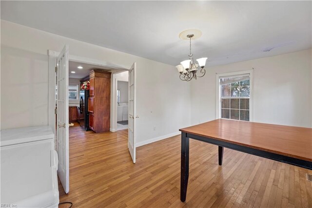 unfurnished dining area featuring a chandelier and light hardwood / wood-style flooring