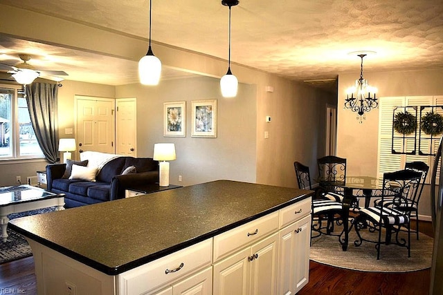 kitchen with white cabinetry, ceiling fan with notable chandelier, a center island, dark wood-type flooring, and pendant lighting