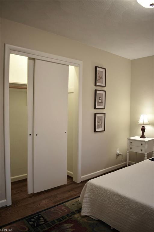 bedroom with dark wood-type flooring and a closet