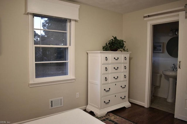 bedroom featuring dark wood-type flooring, sink, and ensuite bath