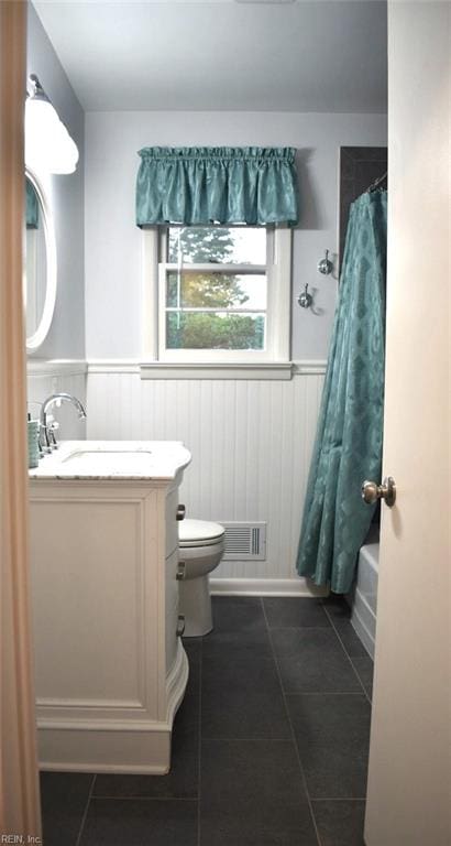 full bathroom featuring vanity, shower / bath combo with shower curtain, tile patterned flooring, and toilet