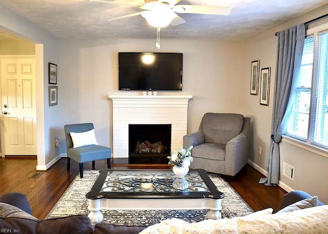 living room featuring a brick fireplace, plenty of natural light, and dark wood-type flooring