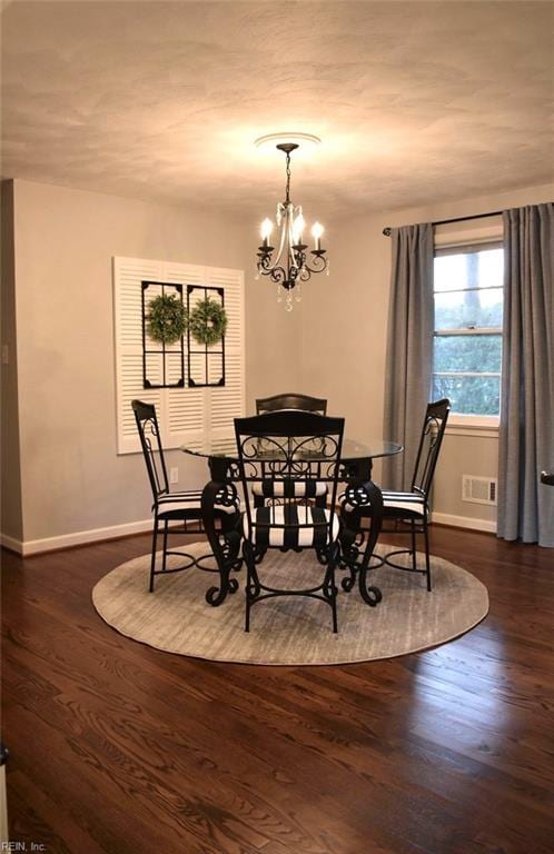 dining area featuring dark wood-type flooring and an inviting chandelier