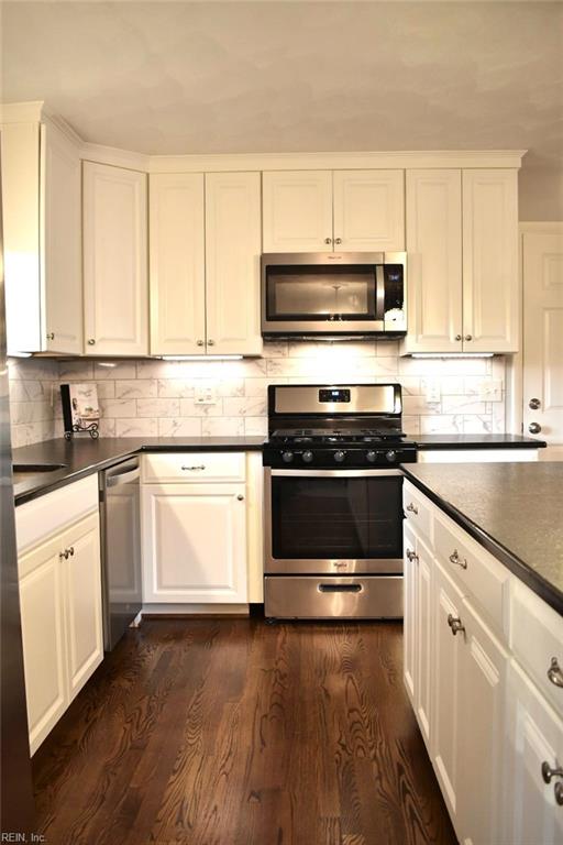 kitchen with white cabinetry, stainless steel appliances, and dark hardwood / wood-style flooring