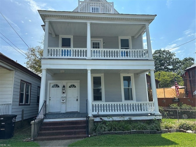 view of front of house featuring covered porch, a front lawn, and a balcony