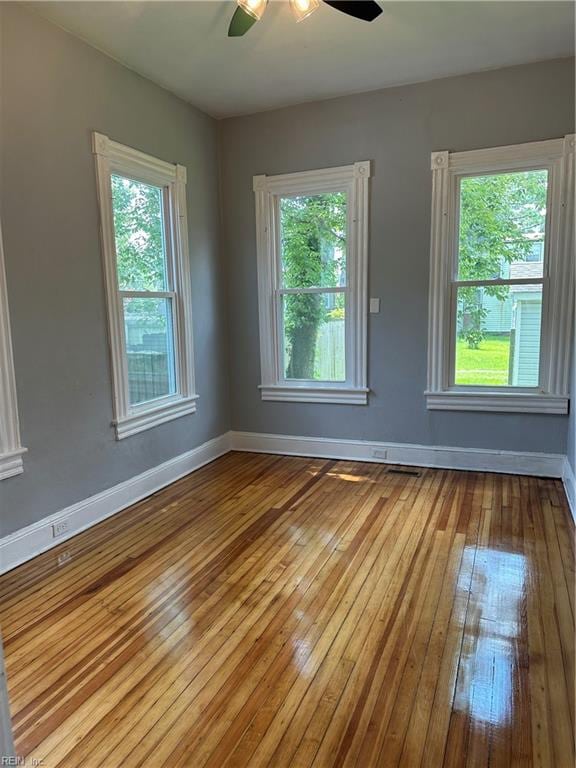 empty room with a wealth of natural light, light hardwood / wood-style floors, and ceiling fan