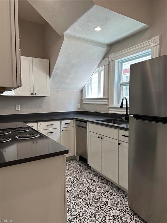 kitchen with white cabinets, sink, lofted ceiling, and stainless steel appliances