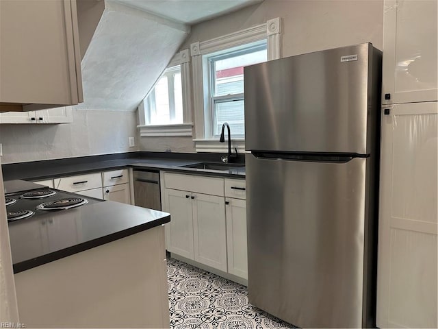 kitchen featuring white cabinetry, sink, vaulted ceiling, and stainless steel refrigerator