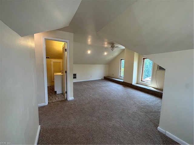 additional living space featuring ceiling fan, dark colored carpet, and lofted ceiling