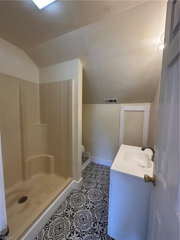 bathroom with walk in shower, lofted ceiling, and vanity