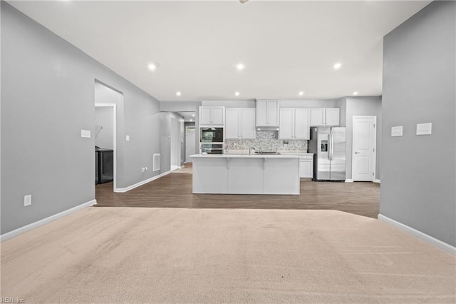 kitchen featuring light hardwood / wood-style floors, white cabinets, a center island with sink, and stainless steel appliances